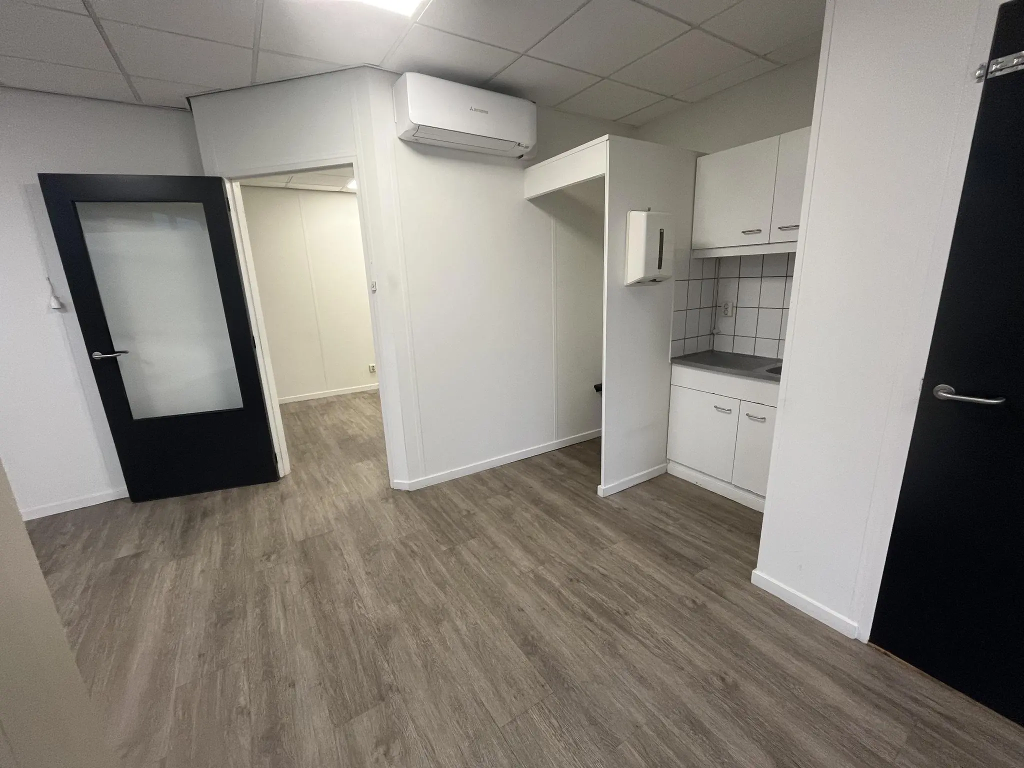 Kleine kitchenette met witte kasten in een kantoorruimte aan de Burgemeester Smitsstraat.